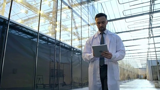 穿着实验服的人在用平板电脑