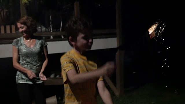 10 -11岁的男孩和家人在院子里玩烟花和烟花