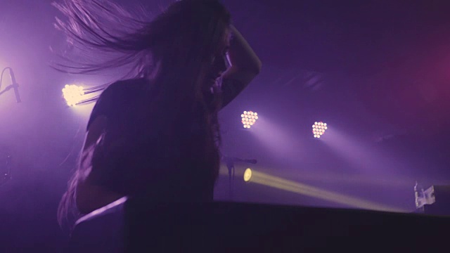 在夜总会里，一位年轻漂亮的女DJ在调音台播放音乐