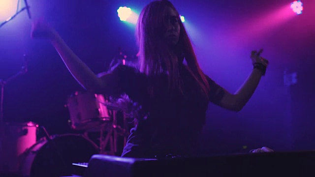 在夜总会里，一位年轻漂亮的女DJ在调音台播放音乐