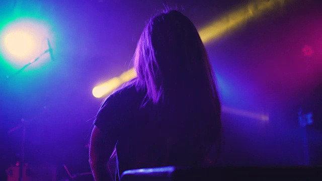 在夜总会里，一位年轻漂亮的女DJ在调音台播放音乐