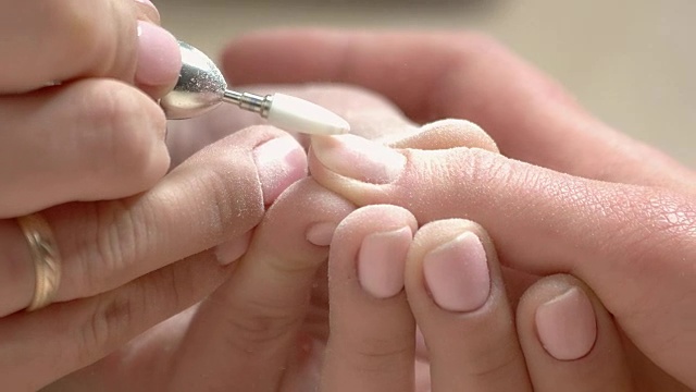 美容师用铣刀清洁指甲。