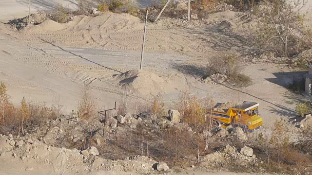 详情图-采矿卡车在巨大的露天矿山，重型采矿卡车装载着铁矿石在露天采石场上，俯视