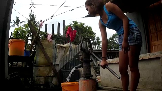 女士手动从深井抽水，由于缺乏水设施的偏远住宅社区