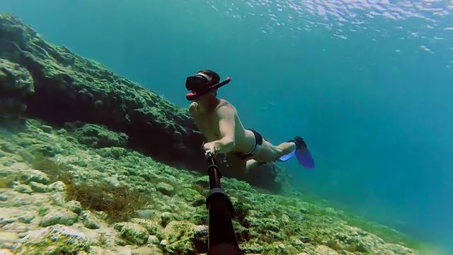 详情图-年轻男子潜水时戴着通气管拍摄水下视频