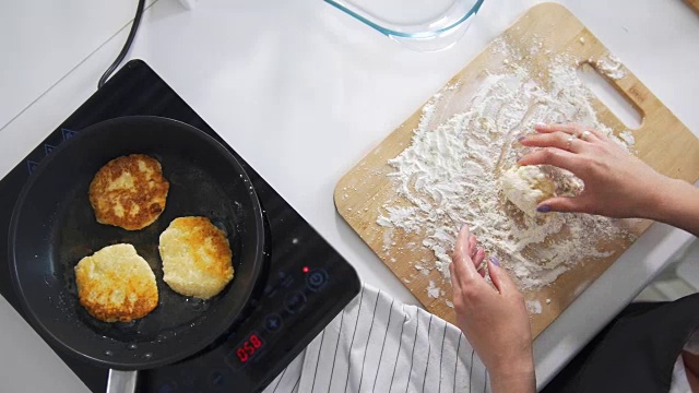 女人用手在平底锅里煎自制的奶酪煎饼