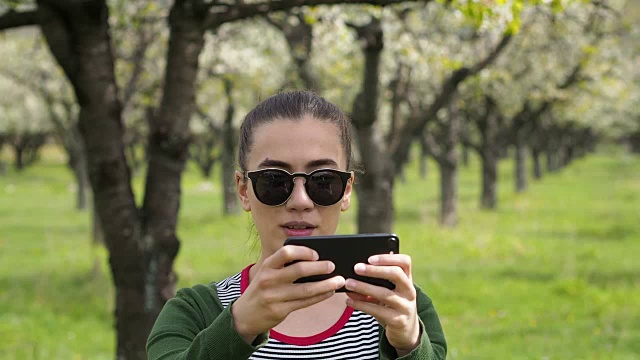 年轻的白人女人戴着墨镜用手机拍照