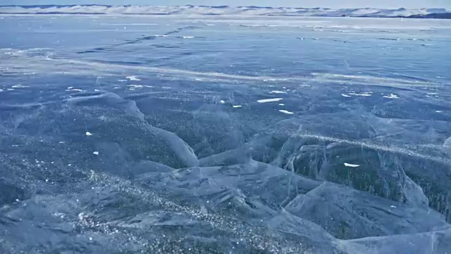 詳情圖-雪在冰面上飛舞。雪花在貝加爾湖的冰面上飛舞。冰非常美麗，有獨特的裂縫。背景視圖山景。雪花閃耀著紅光。