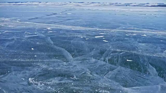 詳情圖-雪在冰面上飛舞。雪花在貝加爾湖的冰面上飛舞。冰非常美麗，有獨特的裂縫。背景視圖山景。雪花閃耀著紅光。