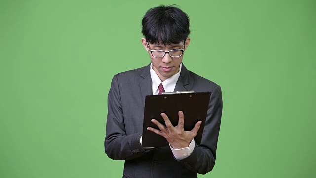 年轻的亚洲商人一边看书一边聊天