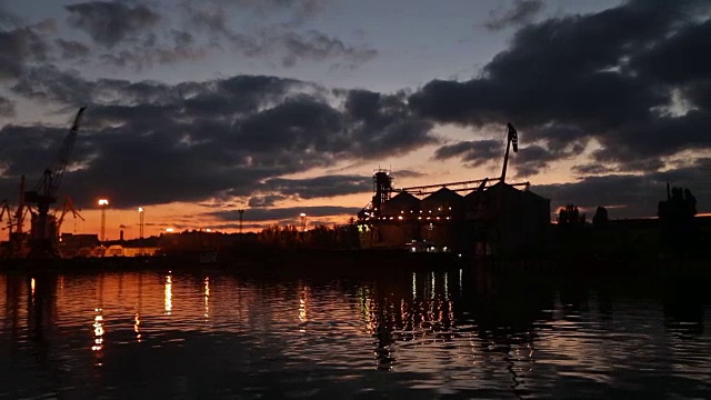 傍晚海港的大型粮食码头全景。谷物散货在夜间转船。从泊位的大型电梯装载粮食作物上船。选择性聚焦和散景