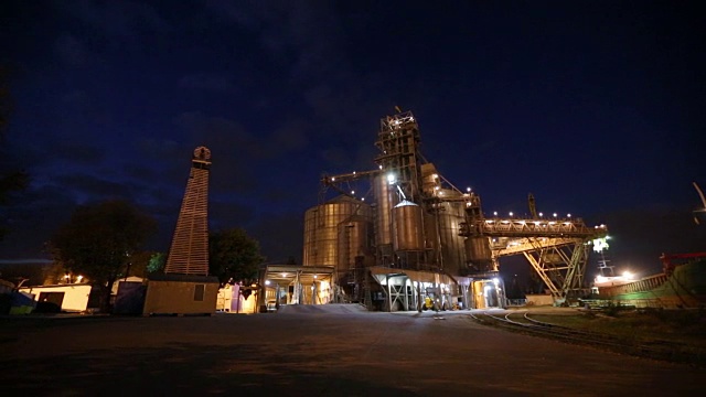 夜间全景图的粮食作物装载在散货船船通过后备箱打开货仓仓在海港从卡车。谷物主要转运。运输农产品