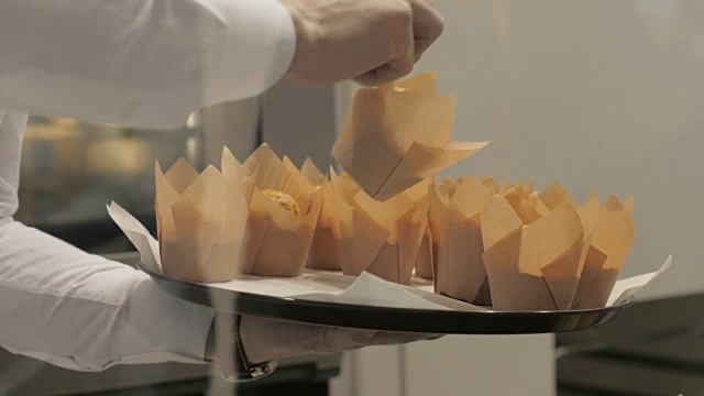 面包师在烘焙店放纸包装的松饼