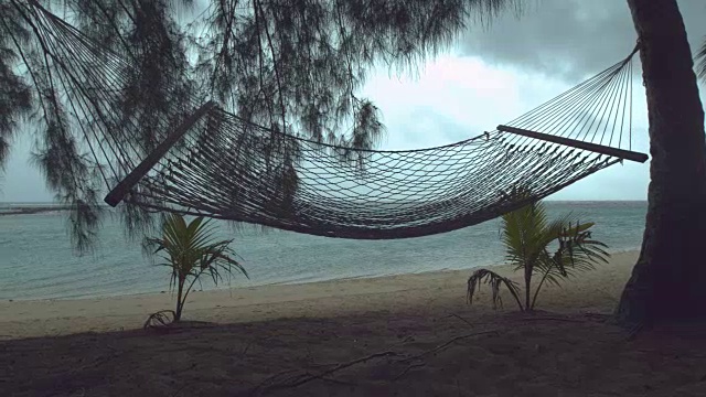 慢镜头:热带海滩上孤独的吊床在狂风暴雨中摇摆。