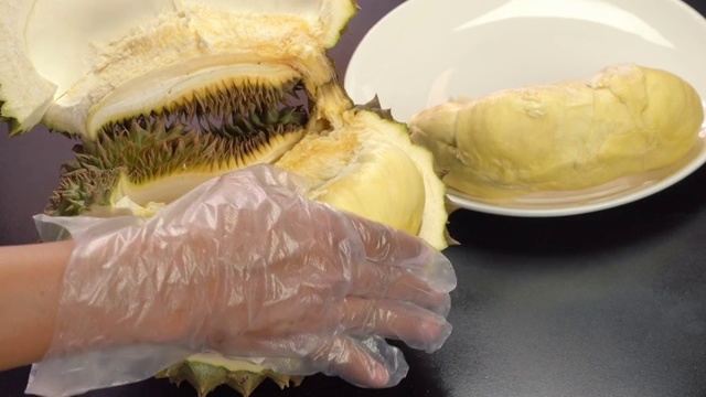 手把去皮的榴莲放在白色盘子上