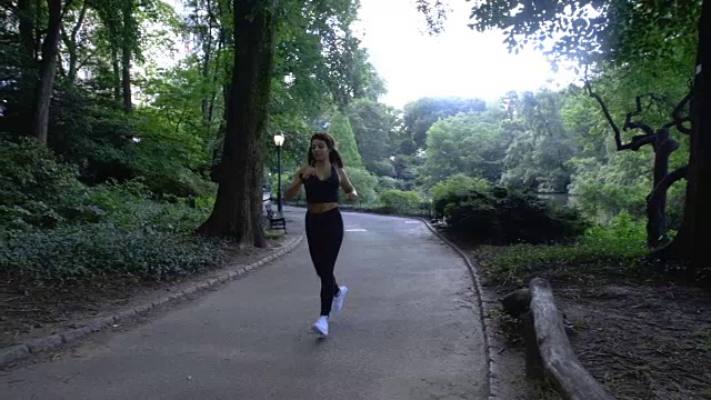 一个阳光明媚的早晨，年轻的白人女子在公园里慢动作跑步