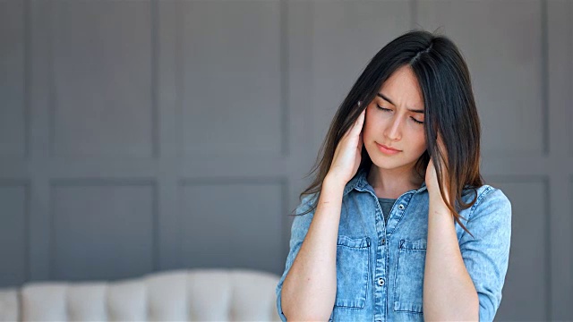 饱受压力或头痛折磨的女性在家痛苦地扮鬼脸