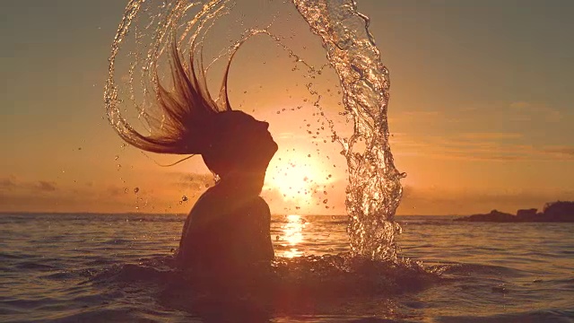 詳情圖-剪影:一名年輕女子把她的頭發(fā)甩到后面，在夕陽下潑水。