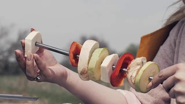 女性手串蔬菜串在烤肉串在户外野餐