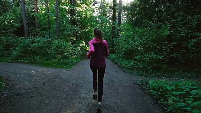 年轻的女孩在森林里奔跑，一个女人在夏天的公园里慢跑，慢镜头