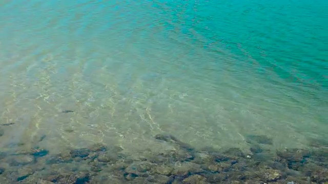 清澈的海水，清澈的海水，沙底有石头。碧绿的海水和充满异国情调的海滩上平静的海浪