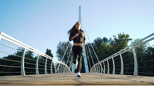 活跃的女人在城市人行桥上慢跑跑步。