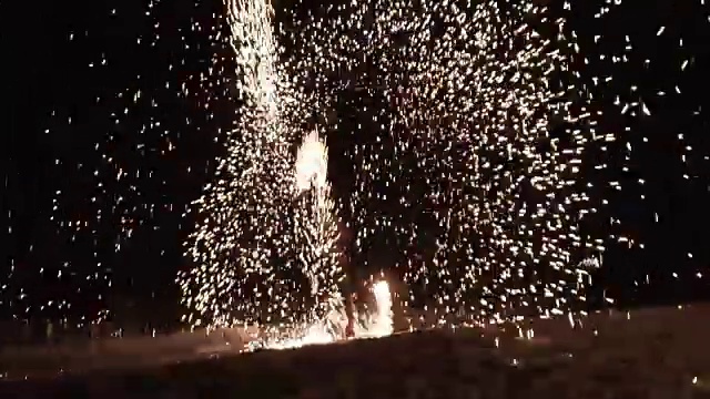 一个人旋转点燃铁丝羊毛火表演，惊人的烟花夜生活在海滩上表演