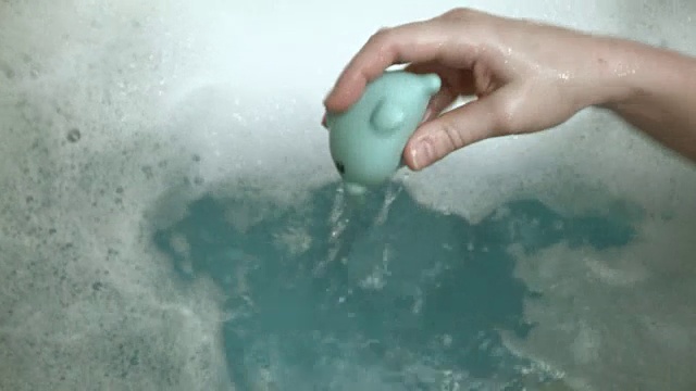 详情图-一个白人小男孩在他的浴缸里玩耍和清洁，而他的妈妈用一个玩具喷射他