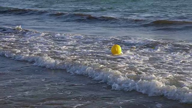 黄色浮标在海水中缓慢移动。浮在水波上的海上浮标。