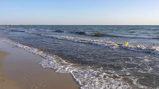 在海滩的深水中漂浮的黄色浮标慢镜头