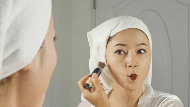 美丽的女人看着镜子，在脸上画轮廓