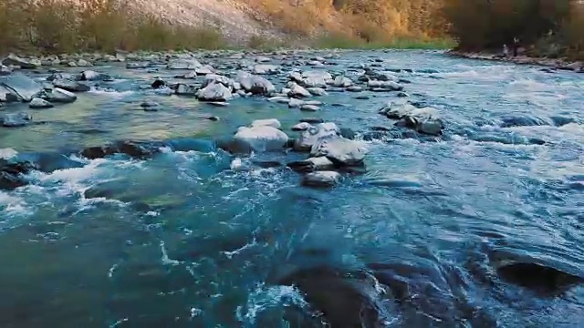 低空俯瞰奔流的山河，和晶莹的绿松石之间的山脉。日落时间。太阳光发出橙色的光斑。治疗泌尿系统疾病和前列腺炎、肾结石的概念，自由决定
