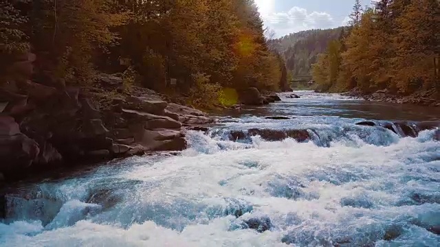 低空急速飞过奔流的山河和瀑布，蓝色的森林和群山中间。日落时间。太阳光发出橙色的光斑。治疗泌尿系统疾病和前列腺炎的理念，决策自由